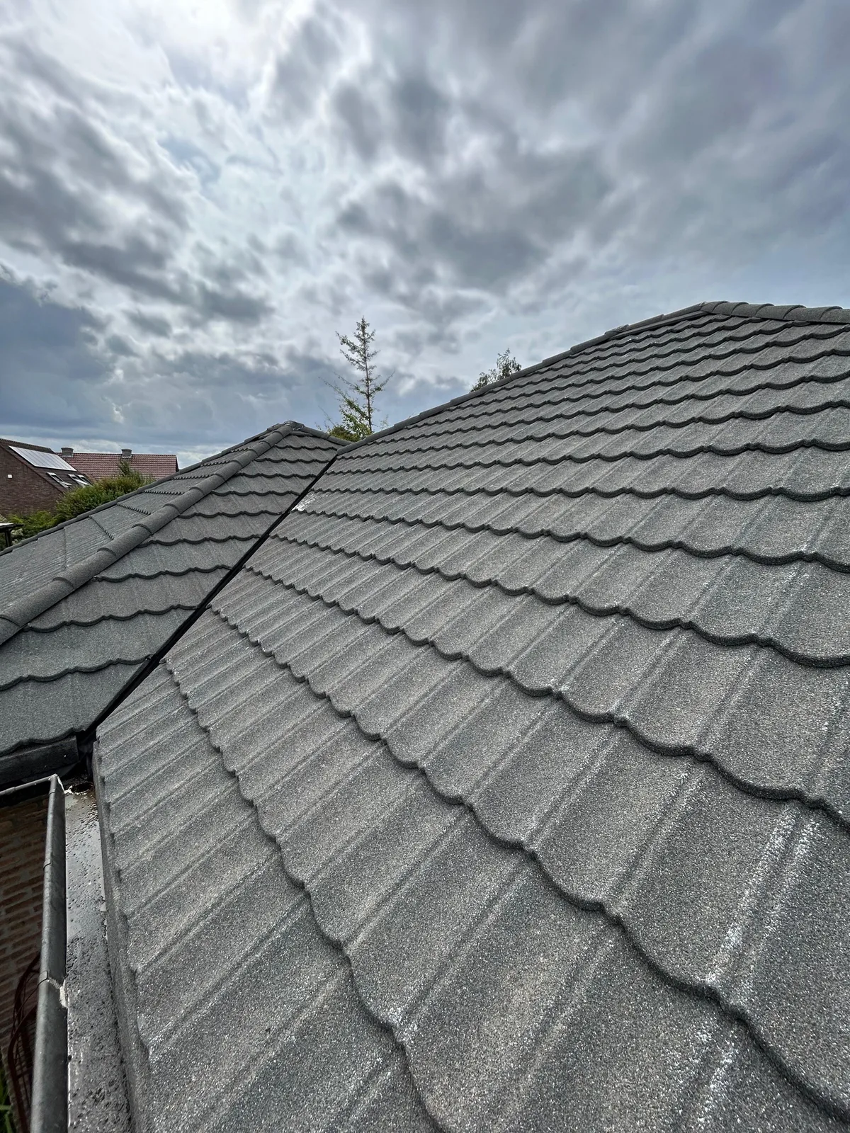 Hetzelfde dakvlak na de dakreiniging: egaal antracietgrijze betonpannen zonder mos, algen of korstmos